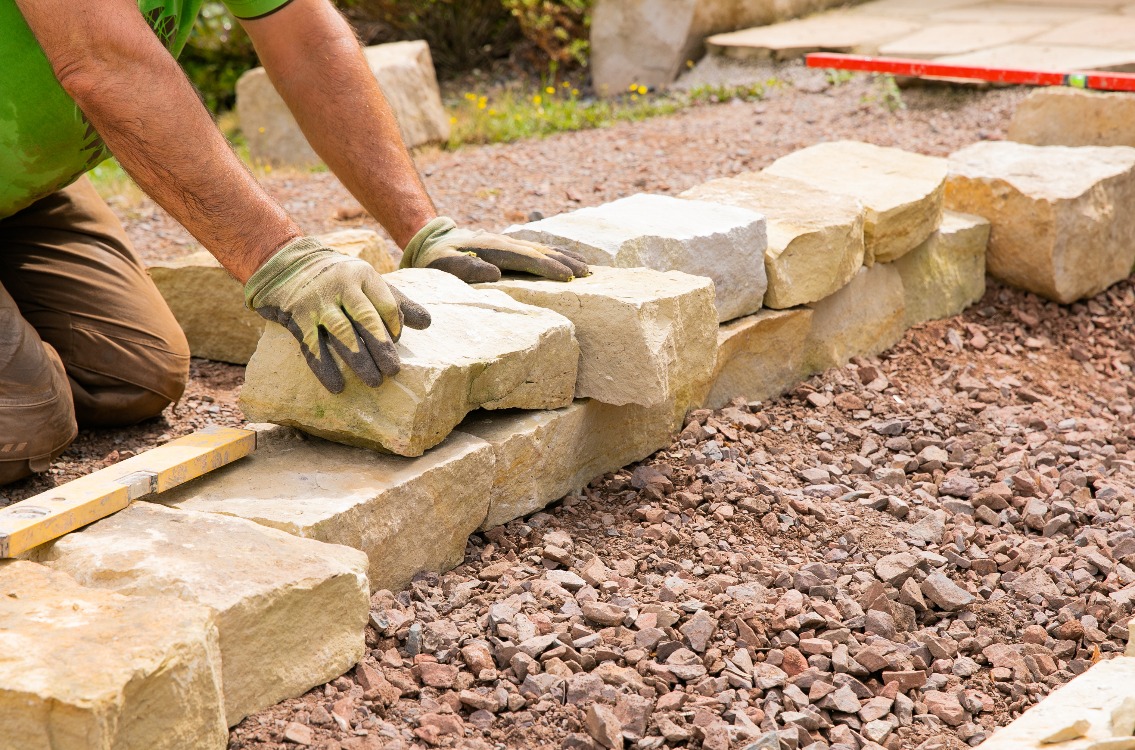 Man landscaping with natural stones -  Building of a dry stone wall